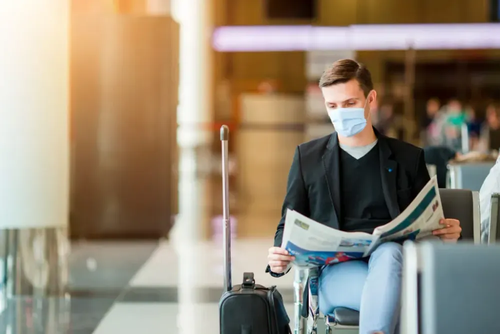 Man reading a newspaper, wearing a mask in an airport terminal